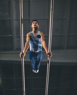Little male gymnast training in gym, flexible and active. Caucasian fit little boy, athlete in sportswear practicing in exercises for strength, balance.