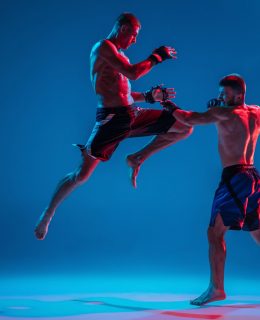 MMA. Two professional fighters punching or boxing isolated on blue studio background in neon